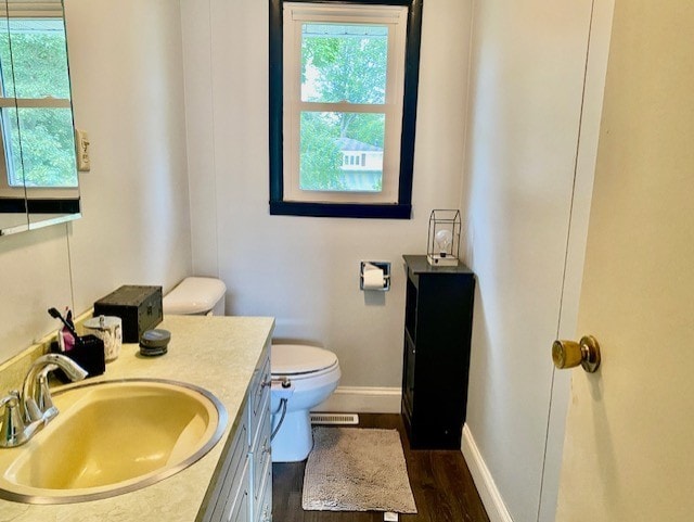 bathroom featuring vanity, wood finished floors, visible vents, baseboards, and toilet