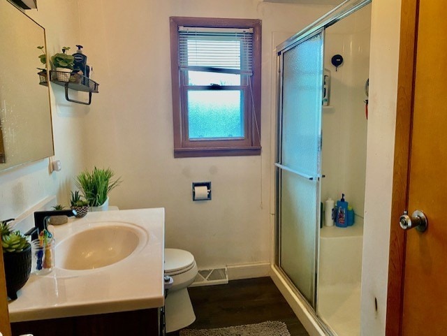 full bathroom featuring toilet, wood finished floors, a shower stall, baseboards, and vanity