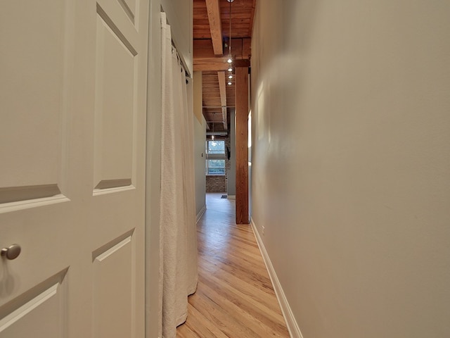 hallway with light hardwood / wood-style flooring, beamed ceiling, and wood ceiling