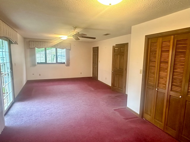 unfurnished bedroom featuring ceiling fan, a textured ceiling, multiple windows, and carpet floors