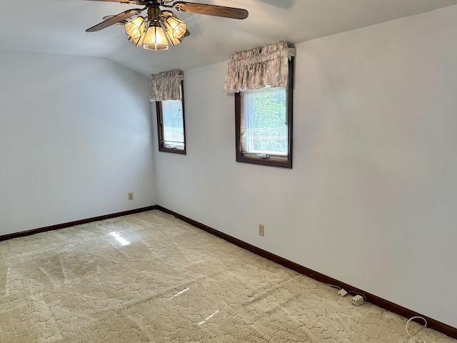 empty room featuring lofted ceiling, baseboards, light colored carpet, and ceiling fan