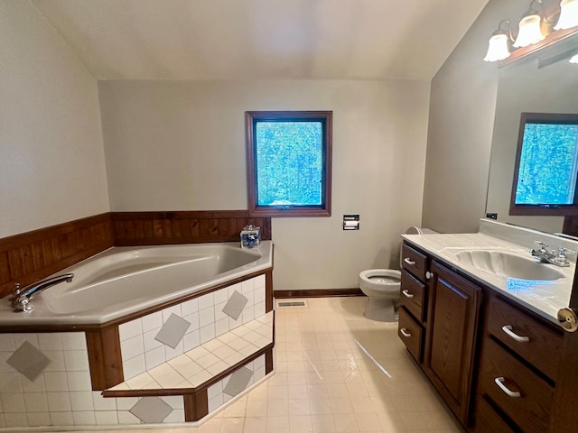 bathroom featuring tile patterned floors, vanity, toilet, and tiled bath