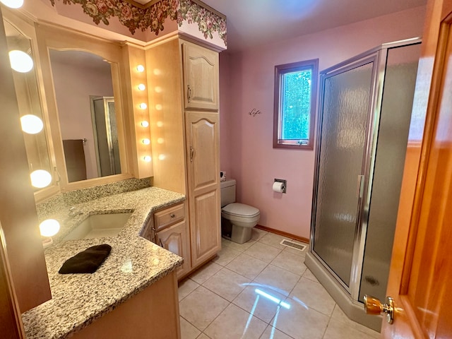 bathroom featuring vanity, toilet, tile patterned flooring, and a shower with shower door