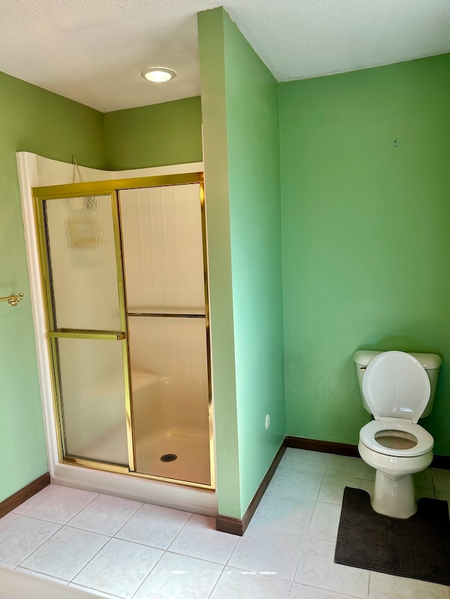 bathroom featuring a textured ceiling, toilet, tile patterned flooring, and a shower with shower door