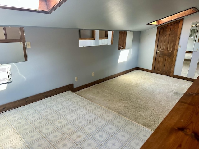 spare room featuring carpet floors, stairway, a skylight, baseboards, and an AC wall unit