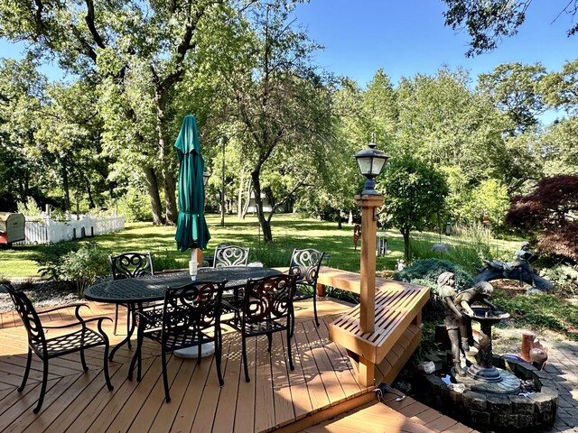 wooden terrace featuring a lawn and outdoor dining space