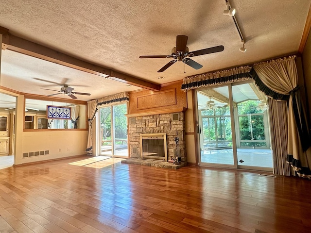 unfurnished living room featuring hardwood / wood-style floors, a ceiling fan, and a textured ceiling