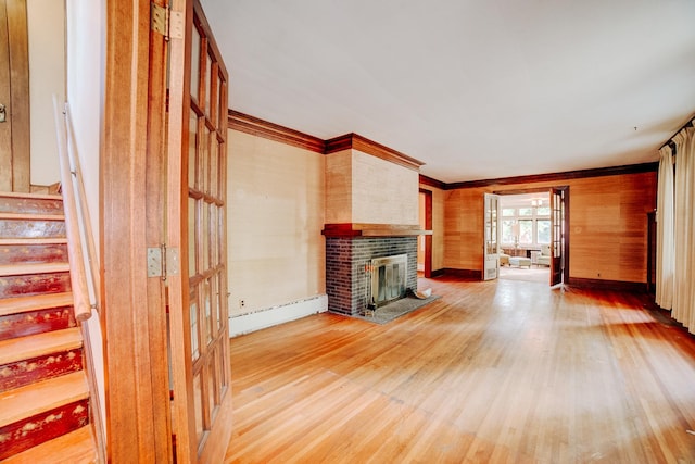 328 E Mulberry St, Watseka, IL 60970 - unfurnished living room featuring a baseboard radiator, a brick fireplace, light wood-style floors, ornamental molding, and stairs