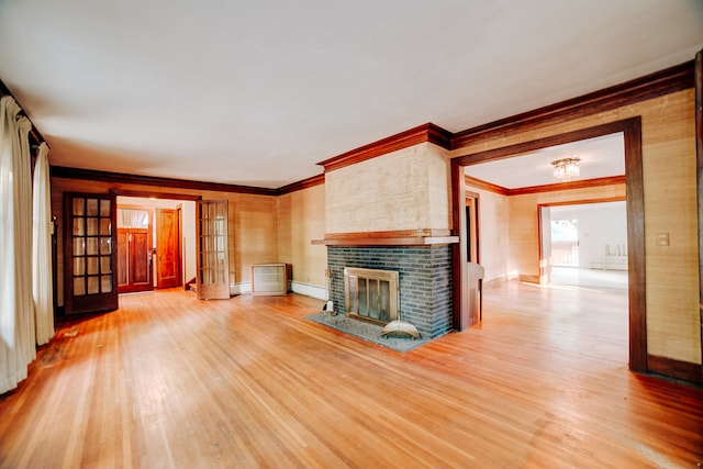 unfurnished living room with a brick fireplace, ornamental molding, french doors, and light hardwood / wood-style floors