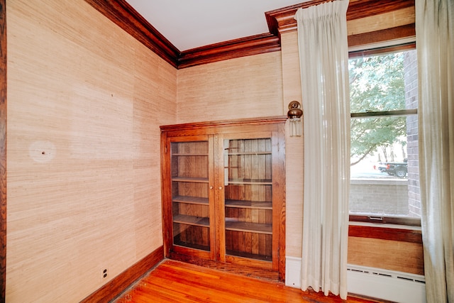 hallway with ornamental molding, a baseboard radiator, and hardwood / wood-style floors