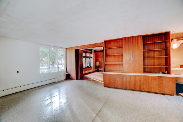 unfurnished living room with wood walls, built in features, and baseboard heating