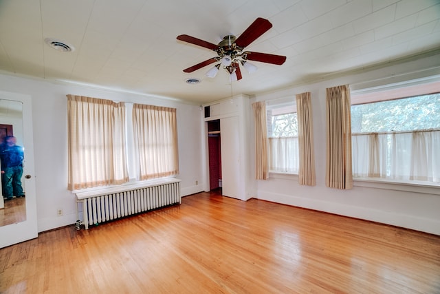 unfurnished bedroom with hardwood / wood-style flooring, ceiling fan, radiator, and a closet