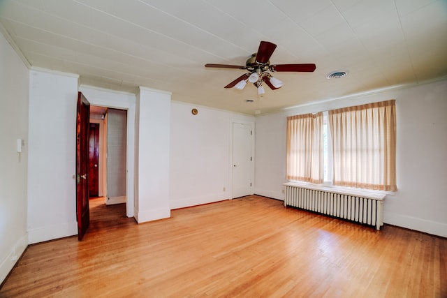 empty room with ornamental molding, hardwood / wood-style flooring, ceiling fan, and radiator