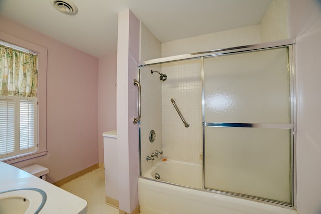 full bathroom featuring combined bath / shower with glass door, vanity, and toilet