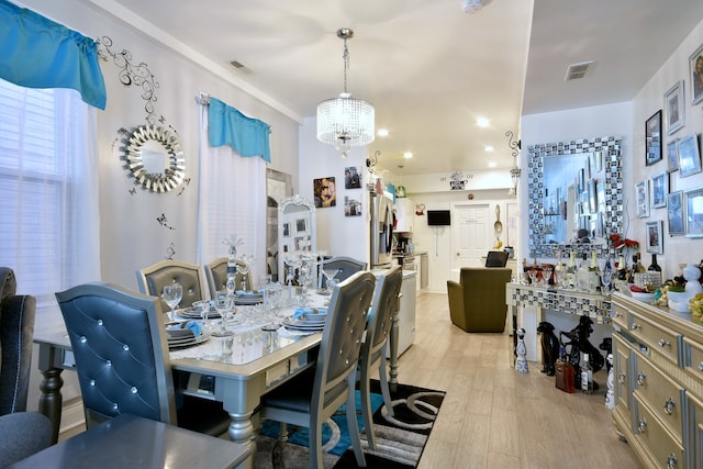 dining room with light hardwood / wood-style flooring, a healthy amount of sunlight, and a chandelier