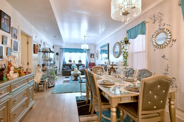 dining room with an inviting chandelier, plenty of natural light, and hardwood / wood-style flooring