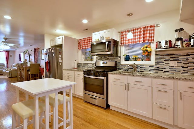 kitchen featuring light hardwood / wood-style flooring, stainless steel appliances, white cabinetry, ceiling fan, and decorative backsplash