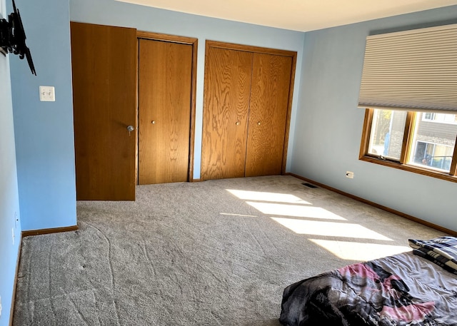 unfurnished bedroom featuring carpet flooring and two closets