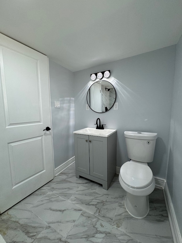 half bath featuring marble finish floor, vanity, toilet, and baseboards