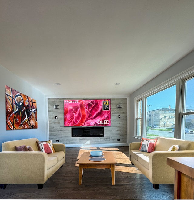 home theater room with an accent wall, wooden walls, and wood finished floors