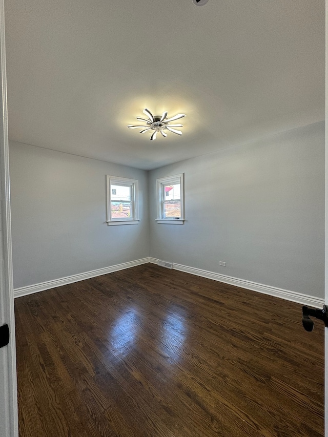 unfurnished room featuring dark wood-type flooring and baseboards