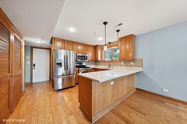 kitchen featuring backsplash, stainless steel appliances, light hardwood / wood-style floors, and decorative light fixtures