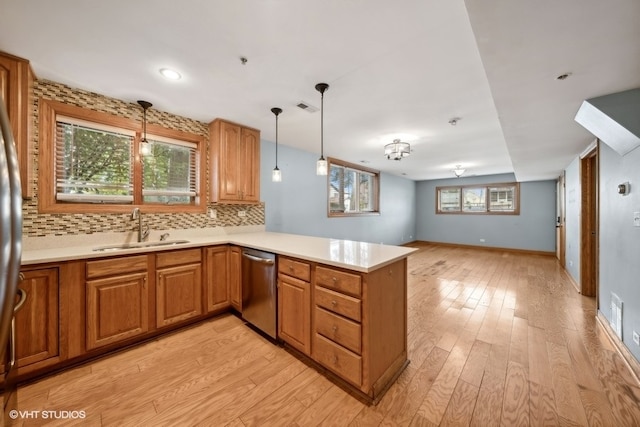 kitchen with kitchen peninsula, dishwasher, a wealth of natural light, light hardwood / wood-style floors, and sink