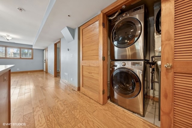 clothes washing area with light wood-type flooring and stacked washer and clothes dryer