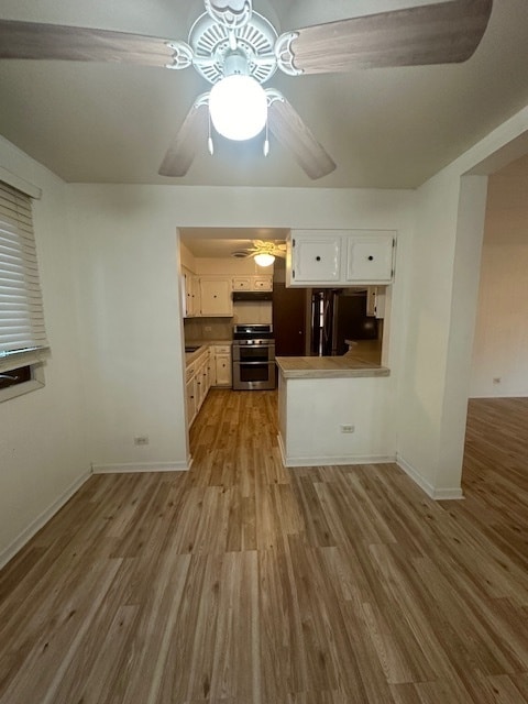 kitchen featuring ceiling fan, stove, light hardwood / wood-style flooring, and white cabinets