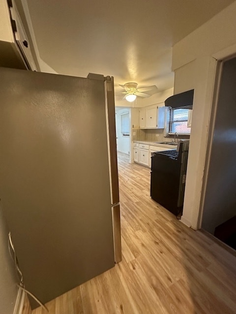 kitchen with white cabinets, ceiling fan, sink, fridge, and light hardwood / wood-style flooring