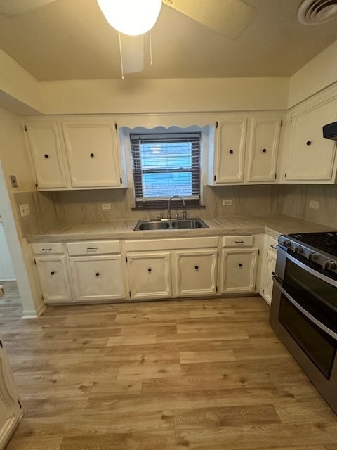 kitchen featuring light hardwood / wood-style flooring, decorative backsplash, white cabinetry, ceiling fan, and sink