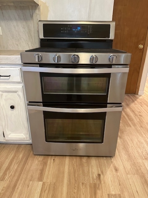 kitchen with light hardwood / wood-style flooring, double oven range, and white cabinetry