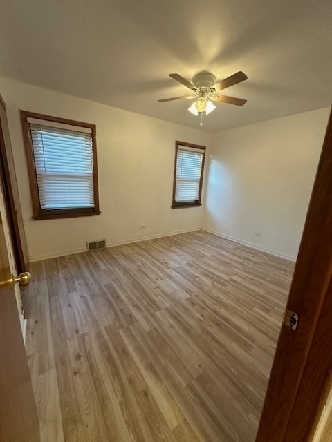 empty room with ceiling fan and light hardwood / wood-style flooring