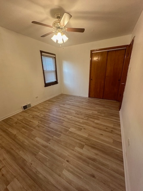 unfurnished bedroom featuring ceiling fan, wood-type flooring, and a closet