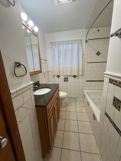 bathroom with tile walls, toilet, vanity, and tile patterned flooring