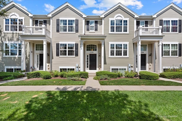 view of front of property featuring a balcony and a front yard