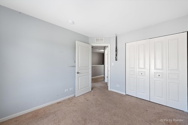 unfurnished bedroom featuring light carpet and a closet