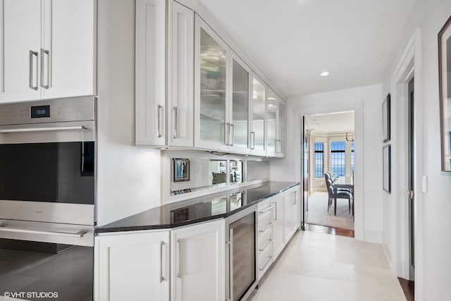 kitchen featuring dark stone countertops, wine cooler, white cabinets, and stainless steel double oven