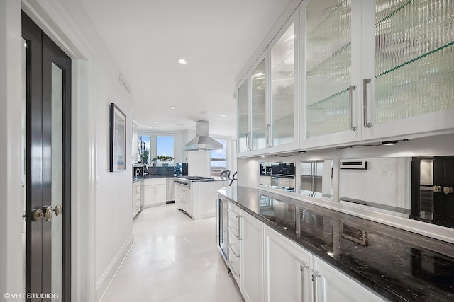 kitchen featuring white cabinetry, dark stone countertops, stainless steel gas cooktop, and island range hood