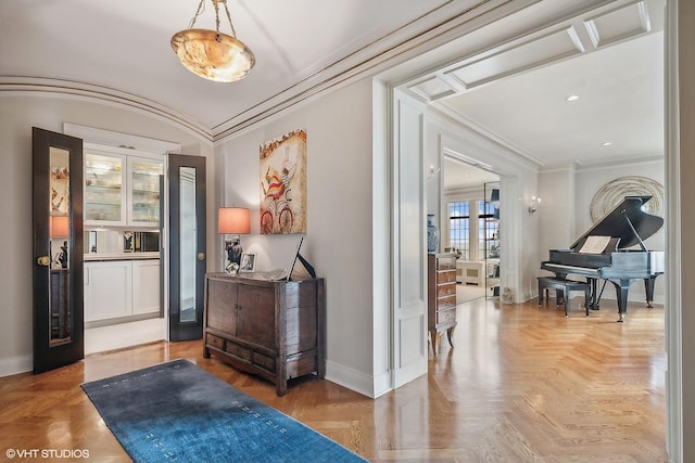 entryway with ornamental molding and parquet flooring