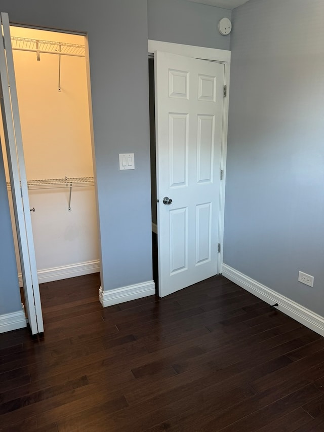 unfurnished bedroom with dark hardwood / wood-style flooring and a closet