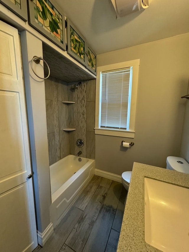 full bathroom with tiled shower / bath, wood-type flooring, vanity, and toilet