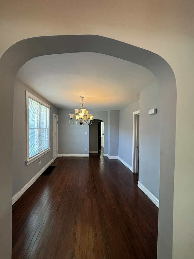 spare room featuring a notable chandelier and wood-type flooring