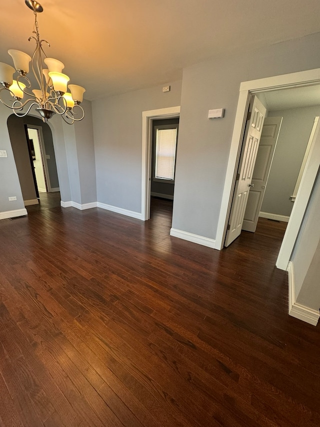 spare room with dark hardwood / wood-style floors and a chandelier