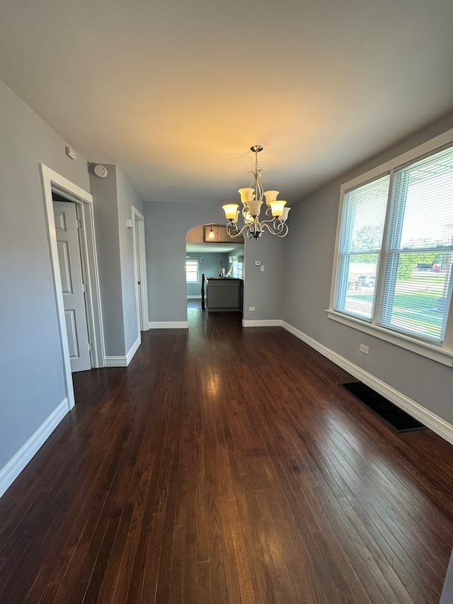 unfurnished dining area with a notable chandelier and dark hardwood / wood-style floors