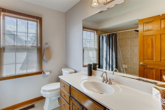 bathroom with vanity, toilet, a wealth of natural light, and tile patterned floors