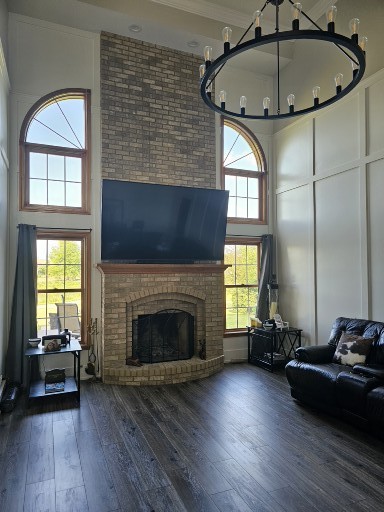 unfurnished living room with a high ceiling, dark hardwood / wood-style floors, an inviting chandelier, and a fireplace