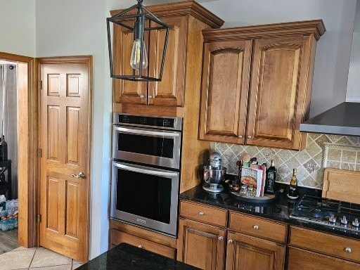 kitchen with tasteful backsplash, gas cooktop, wall chimney range hood, double oven, and light tile patterned flooring