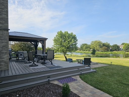 deck with a water view, a yard, and a gazebo