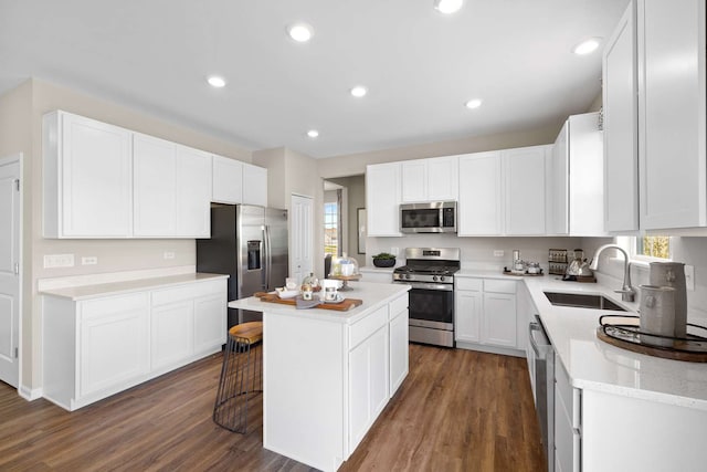 kitchen with dark wood-type flooring, stainless steel appliances, a kitchen island, and sink